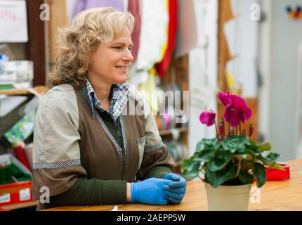 Blumengeschäft mit professionellen Kleidung in einer Baumschule. Konzept der handwerklichen Arbeit mit Blumen. Stockfoto
