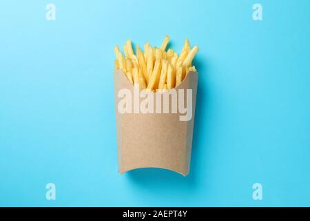 Scheiben heiße Pommes frites in Feld auf blauem Hintergrund, Platz für Text. Ansicht von oben Stockfoto