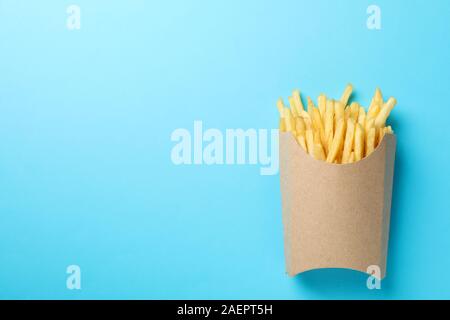 Scheiben heiße Pommes frites in Feld auf blauem Hintergrund, Platz für Text. Ansicht von oben Stockfoto