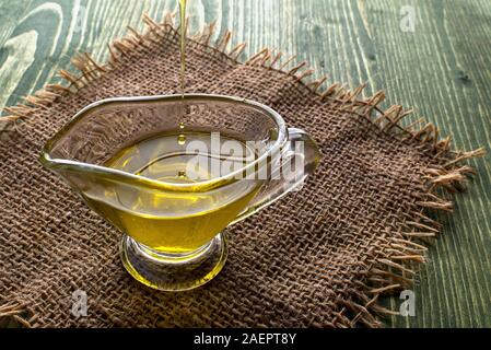Gießen Hanföl in eine Glasschüssel und Hanf Samen in einem Löffel aus Holz, auf einem grünen Hanf-blatt Hintergrund, CBD Hanföl Stockfoto