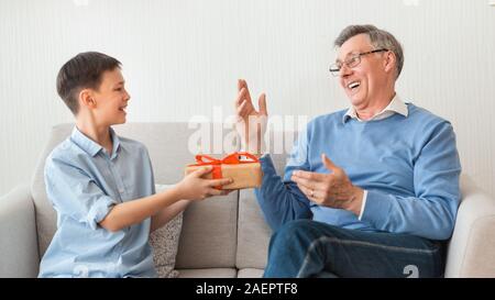 Enkel gratulieren Großvater, verpackte Geschenk Sitzen auf einem Sofa, Panorama Stockfoto