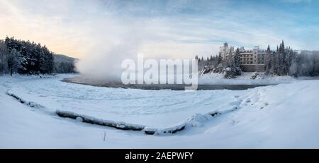 Das schöne Gebäude steht auf der Bank eines zugefrorenen Fluss auf den Sonnenaufgang. Dampf steigt aus dem Fluss. Katun Fluss, Berg Altai, Sibirien, Russland Stockfoto