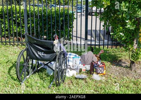 Miami Florida, Hialeah, Parkplatz, Mann, obdachlos, behindert, Rollstuhl, auf Gras schlafen, leere Plastikbehälter, FL191025013 Stockfoto