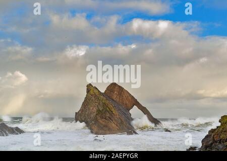 Bogen GEIGE ROCK PORTKNOCKIE Küste von Moray in Schottland stürmischen WINTER WETTER DAS MEER MIT SEHR GROSSEN WELLEN UND EIN BLAUER HIMMEL ÜBER Stockfoto