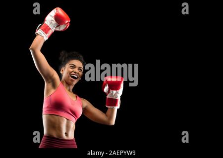 Emotionale afro girl Boxer feiert Erfolg über schwarzen Hintergrund Stockfoto