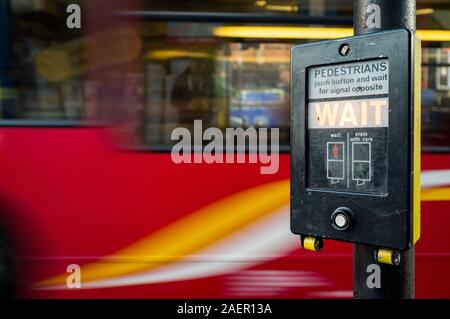 Fußgänger warten! Eine britische Fußgängerüberweg Zeichen mit einer Bewegung verwischt London Bus Hintergrund. Stockfoto