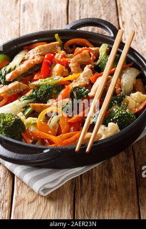 Chinesische braten Schweinefilet mit Broccoli, Bok Choy, Karotten, Paprika, Blumenkohl close-up in einer Pfanne auf dem Tisch. Vertikale Stockfoto