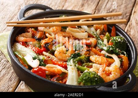 Asiatische gebratene Garnelen, Tintenfisch und Muscheln mit frischem Gemüse der Saison in der Nähe rühren in der Pfanne auf den Tisch. Horizontale Stockfoto