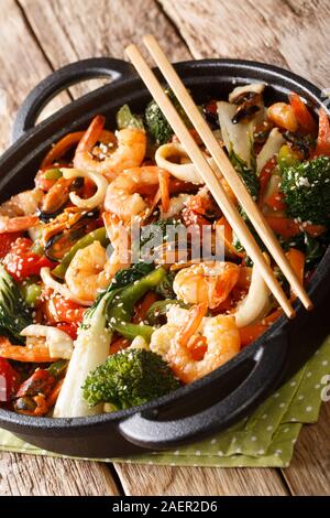 Meeresfrüchte Wokgemüse mit frischem Gemüse close-up in einer Pfanne auf dem Tisch. Vertikale Stockfoto