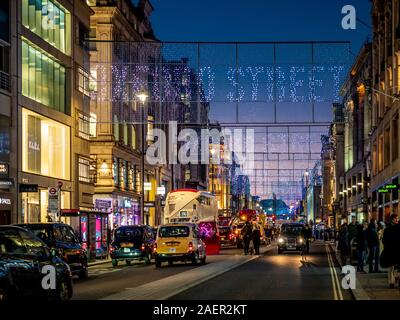 Weihnachtsbeleuchtung in der Oxford Street, London mit Käufern. Stockfoto