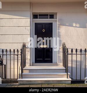 Schwarze Front Tür auf Haus mit Treppen und Geländer. Stockfoto