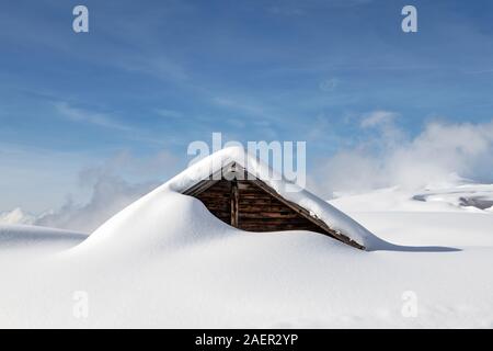 Einem Heuschober in den Bergen ist mit viel frischem Schnee bedeckt. Die weichen Formen der frische Schnee und Schatten erzeugen Symmetrische Leitungen. Diesen Schuppen waren Forme Stockfoto