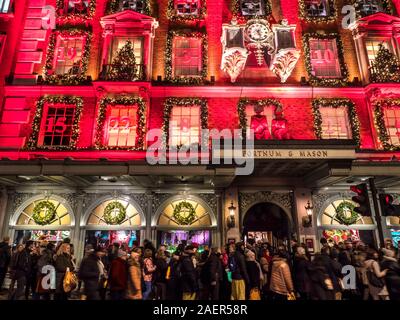 Weihnachten Fortnum & Mason Kaufhaus Fassade, mit einem roten Adventskalender Thema bei Nacht sehr beschäftigt mit Warteschlangen und Menschenmassen Weihnachtskäufer Piccadilly London UK 2019 Stockfoto