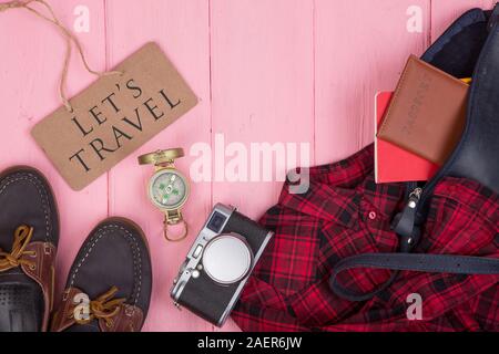 Touristische zeug-bag, Reisepass, Kamera, Kompass, schuhe, t-shirt, Notizen und Blackboard mit Text Wir reisen auf rosa Holz- Hintergrund Stockfoto