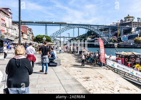 Porto, Nordufer des Douro Flusses ostwärts gegen Luis I Brücke. Touristen Warteschlange Bootsfahrten auf dem Fluss Douro zu nehmen Stockfoto