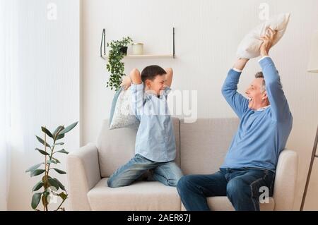 Junge und Großvater Kämpfen mit Kissen auf der Couch zu Hause Stockfoto