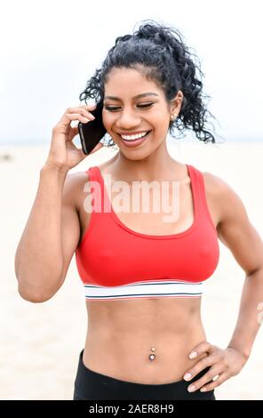 Athletische Frau lächelt und spricht und Handy nach dem Training Stockfoto