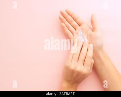 Frau Hände Anwendung creme Pastell rosa Hintergrund mit Kopie Raum isoliert. Bild horizontal, Flach, Draufsicht von oben Stockfoto