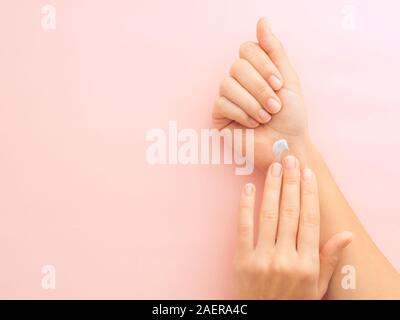 Frau Hände Anwendung creme Pastell rosa Hintergrund mit Kopie Raum isoliert. Bild horizontal, Flach, Draufsicht von oben Stockfoto