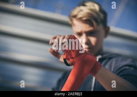 Nahaufnahme der jungen männlichen Händen mit dem Boxen Bands. Junge bereitet für einen Safe Training durch seine Hand wickeln. Boxer bereit, Schläge zu werfen. Teenager Spor Stockfoto