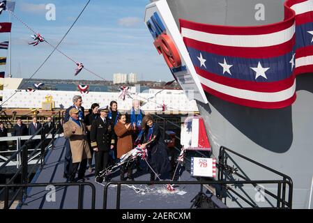 Amb. Caroline Kennedy, rechts, Tochter des verstorbenen Präsidenten John F. Kennedy schwingt eine Flasche Champagner zu Christen der neue Ford-Klasse Flugzeugträger USS John F. Kennedy bei Huntington Ingalls Branchen Dezember 7, 2019 in Newport News, Virginia. Kennedy ist das zweite Schiff in der nächsten Generation des Ford-Klasse der Atom-Flugzeugträger und die zweite amerikanische Flugzeugträger genannt für Präsident Kennedy, mit dem ehemaligen aus dem Dienst im Jahr 2007 in den Ruhestand. Stockfoto