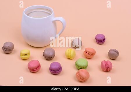 Weiße Tasse duftenden Cappuccino mit Makkaroni Kuchen auf orangem Hintergrund, Ansicht von oben Stockfoto