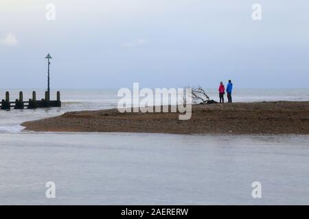 Leute stehen am Kieselstrand. Mündung des Flusses Axe in Devon Stockfoto