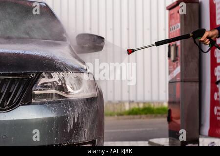 Ein Mann ist ein Auto waschen an Self-Service-Autowaschanlage. Hoher Druck Fahrzeug Waschmaschine sprays Schaum. Stockfoto