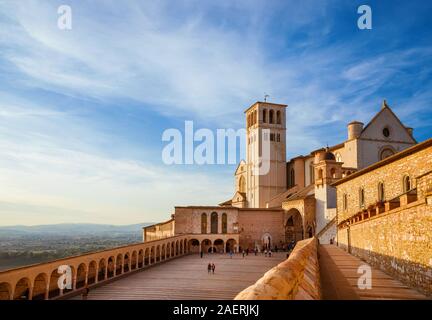 Touristen besuchen Sie die berühmte Basilika des Heiligen Franziskus von Assisi in Umbrien bei Sonnenuntergang Stockfoto