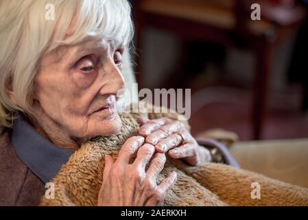 Die 90 Jahre alte Dame ist in einem isolierenden Decke abgedeckt, um warm zu bleiben, als sie sehr sensative auf das kalte Wetter und die Heizkosten sind e Stockfoto