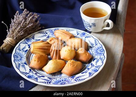 Lavendel madeleines auf einem porzellanteller auf blauem Hintergrund. Im rustikalen Stil. Stockfoto