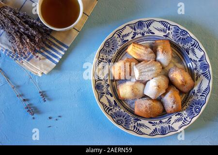 Lavendel madeleines auf einem porzellanteller auf blauem Hintergrund. Im rustikalen Stil. Stockfoto