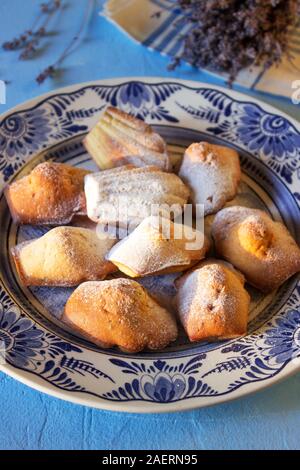 Lavendel madeleines auf einem porzellanteller auf blauem Hintergrund. Im rustikalen Stil. Stockfoto