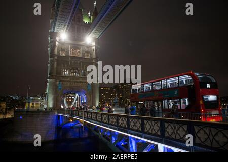 Red Bus kreuze Tower Bridge bei Nacht GV Allgemeine Ansicht, London Stockfoto