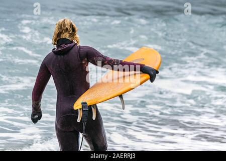 Arktis Surfer Surfen in der Norwegischen See. Unstad, Norwegischen Dorf auf der Lofoten. Norwegische Küste. Winter Wasser Sport. Stockfoto