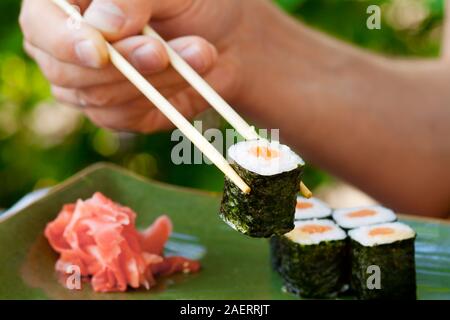 Man's Hand, die Sushi mit Stäbchen, Japanisch Meeresfrüchte Stockfoto