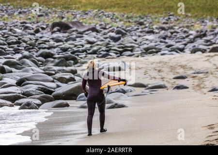 Arktis Surfer Surfen in der Norwegischen See. Unstad, Norwegischen Dorf auf der Lofoten. Norwegische Küste. Winter Wasser Sport. Stockfoto