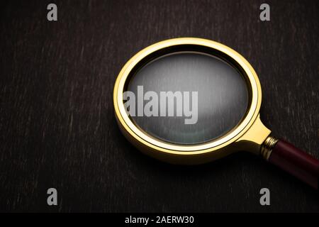 Goldene Lupe auf einem dunklen Hintergrund. Stockfoto