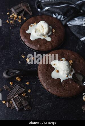 Nahaufnahme von Brownies mit Eis und Muttern in Gusseisen skillets. Stockfoto