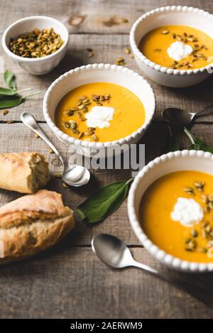 Blick von oben auf die Schalen von butternut Kürbis Suppe auf rustikalen Holztisch. Stockfoto