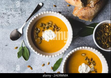 Nahaufnahme von Schalen mit butternut Kürbis Suppe auf grauem Hintergrund. Stockfoto