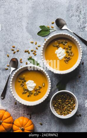 Blick von oben auf die Schalen von butternut Kürbis Suppe auf grauem Hintergrund. Stockfoto