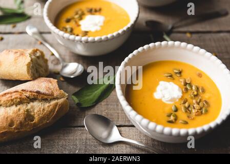 Nahaufnahme von Schalen mit butternut Kürbis Suppe auf rustikalen Holztisch. Stockfoto