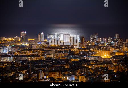 Barcelona Skyline bei Nacht mit dem Mond über dem Meer Stockfoto