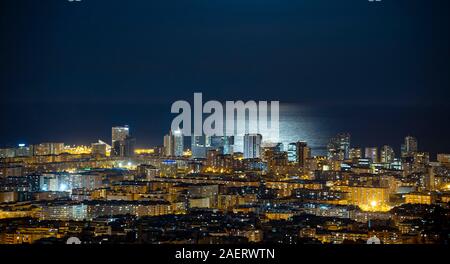 Barcelona Skyline bei Nacht mit dem Mond über dem Meer Stockfoto