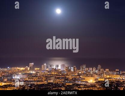 Barcelona Skyline bei Nacht mit dem Mond über dem Meer Stockfoto