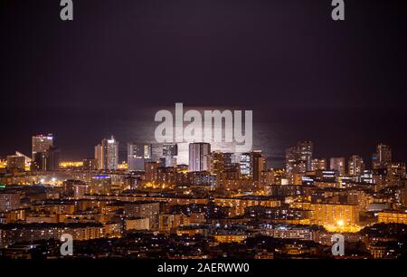 Barcelona Skyline bei Nacht mit dem Mond über dem Meer Stockfoto