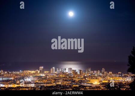 Barcelona Skyline bei Nacht mit dem Mond über dem Meer Stockfoto