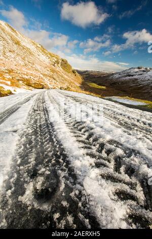 Reifenspuren auf dem Wrynose-Pass die geschlossen wurde, durch Schnee und Eis, Lake District, Großbritannien Stockfoto