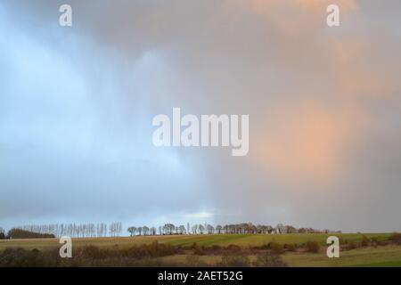 Ein Sturm aus einer Reihe von Schauern passiert Eynsford und Lullingstone in Kent, England, und erzeugt Regenbogen und bunte Wolken. Wintersturm, Regenfall Stockfoto